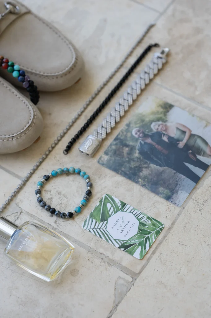 Arthur-Andrea-Jamaica-Halfmoon-Wedding-069.jpg - OMOS Photography Flat lay of beige loafers with colorful beaded bracelets and braided silver bracelets on a light tiled floor, beside a small wedding photo.