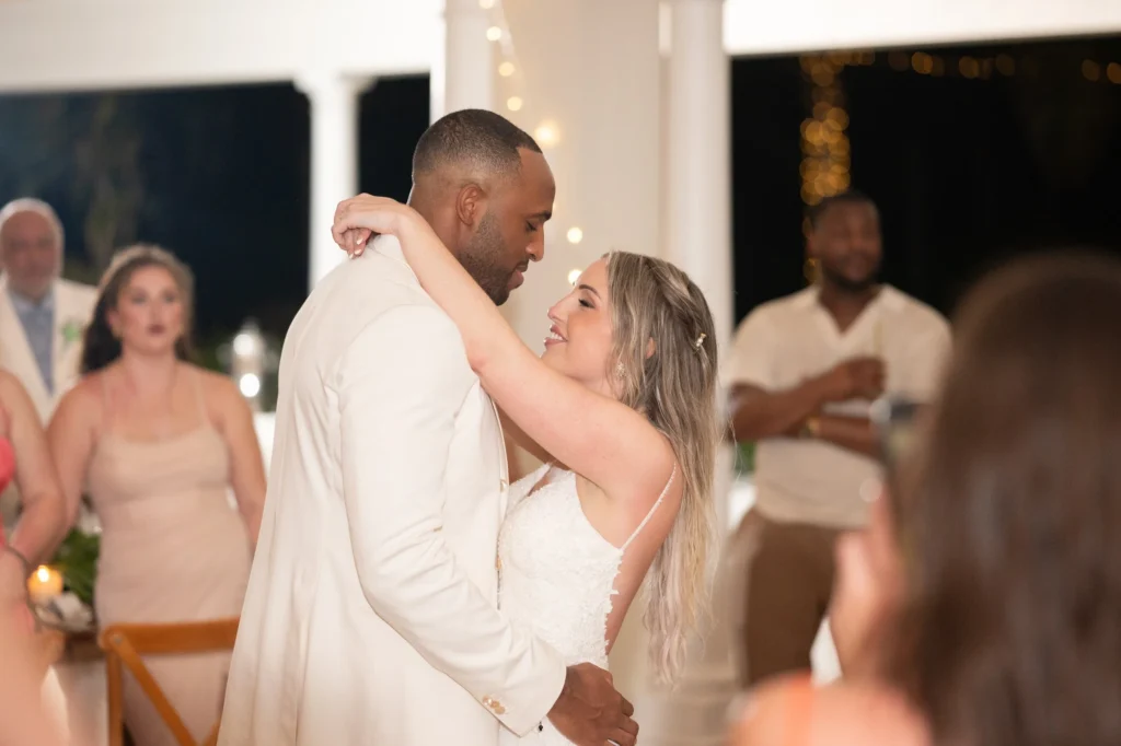 Arthur-Andrea-Jamaica-Halfmoon-Wedding-479.jpg - OMOS Photography Bride and groom dance closely at their wedding, embracing as guests look on in the background.