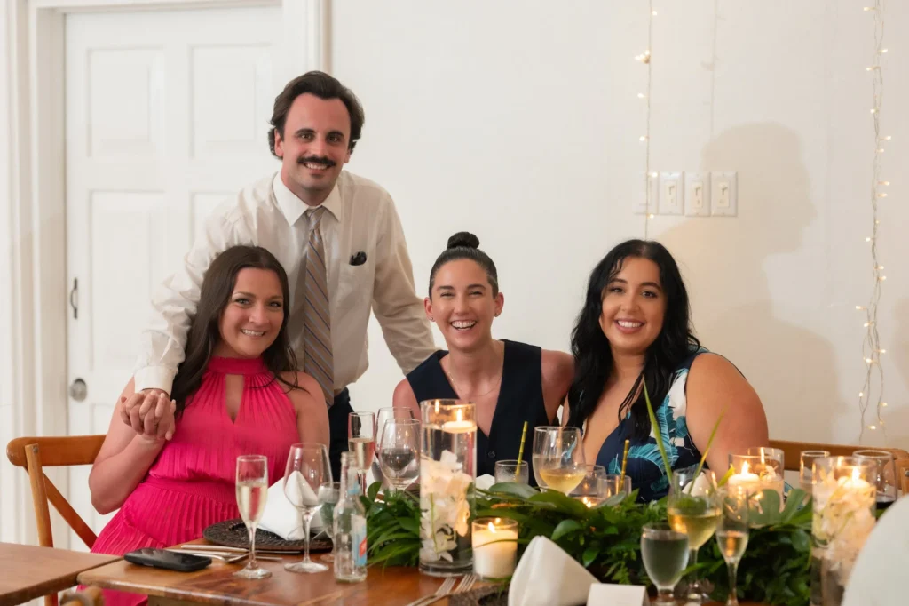 Arthur-Andrea-Jamaica-Halfmoon-Wedding-496.jpg - OMOS Photography Four friends posing and smiling at a dinner table with candles and drinks around them.
